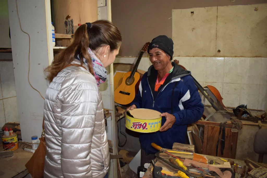 Al taller, un luthier ensenya a Lana Kovačević la caixa d'un instrument feta amb una llauna de conserva.